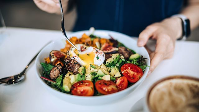 A woman sits down to enjoy a keto-friendly meal. Low-card, high-fat diets may be helpful in managing epilepsy, but require guidance from a healthcare provider.