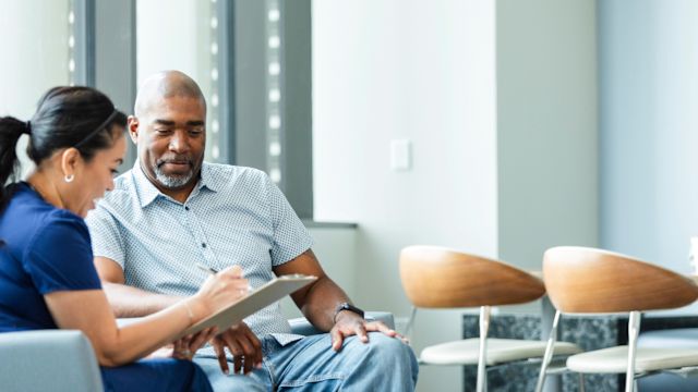 A male patient talks to his oncologist in a common area of a cancer care center.