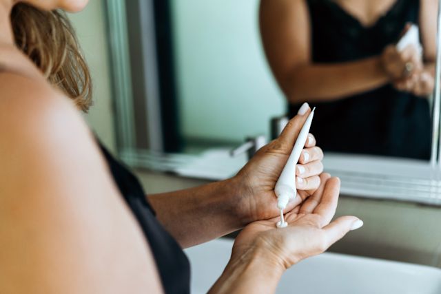 Woman putting lotion on hand to apply to psoriasis