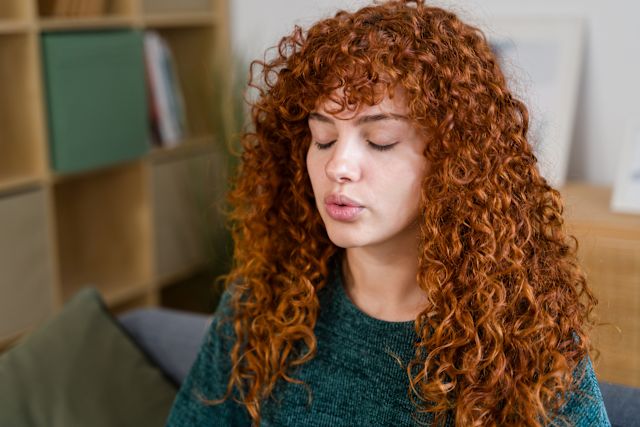 young red-haired woman taking a deep breath