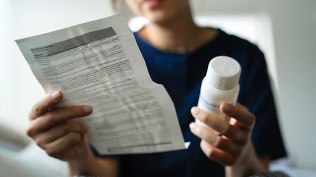 A woman reads the prescribing information for a targeted therapy she has started taking to treat ISM.