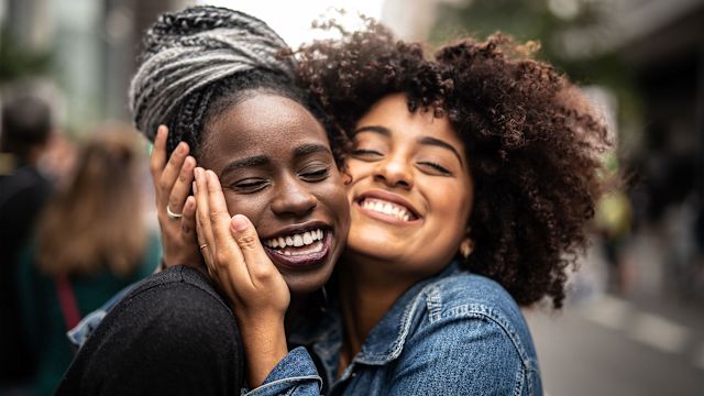 Two young black women embracing one another