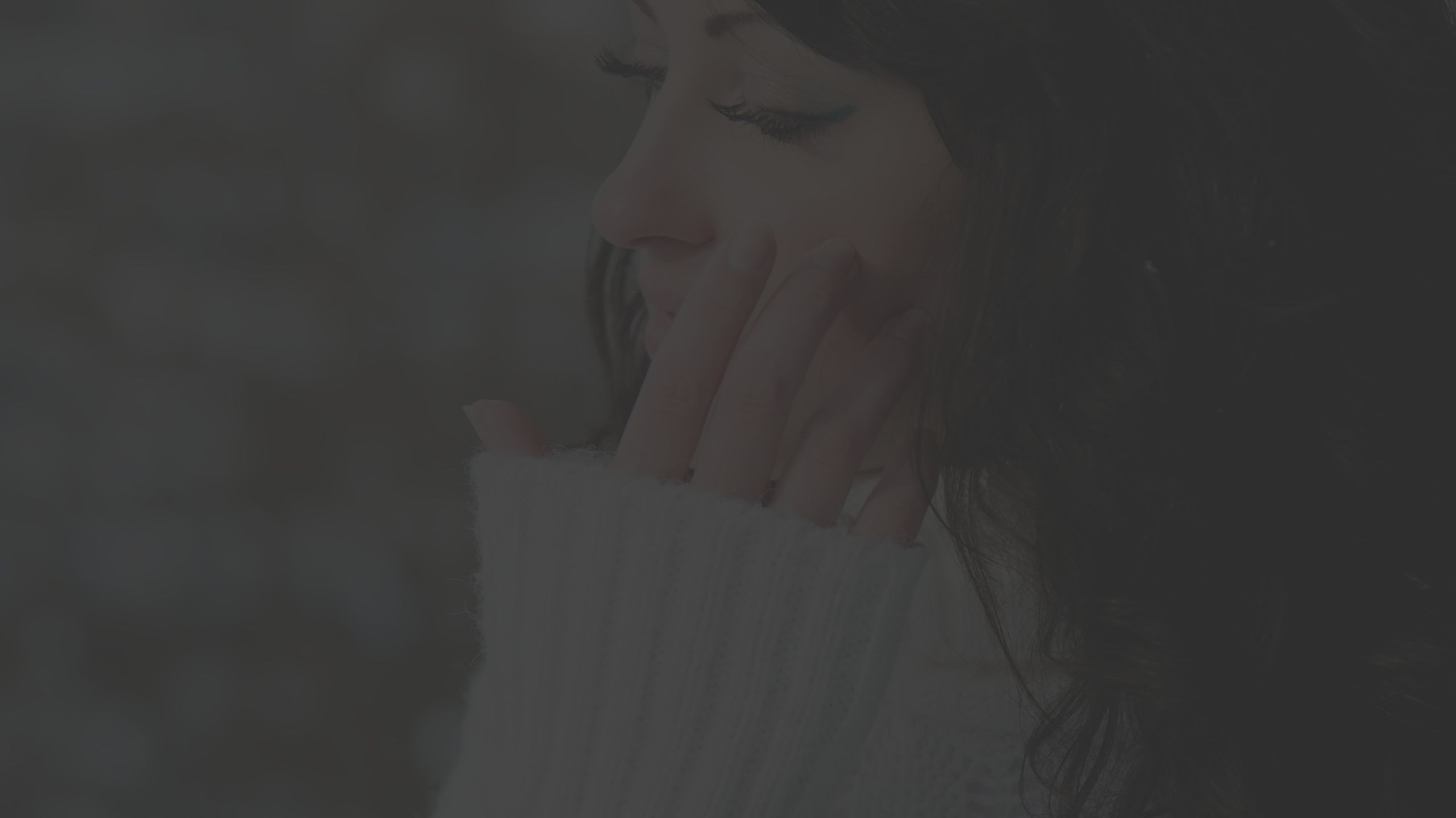 woman, white sweater, hand touching face