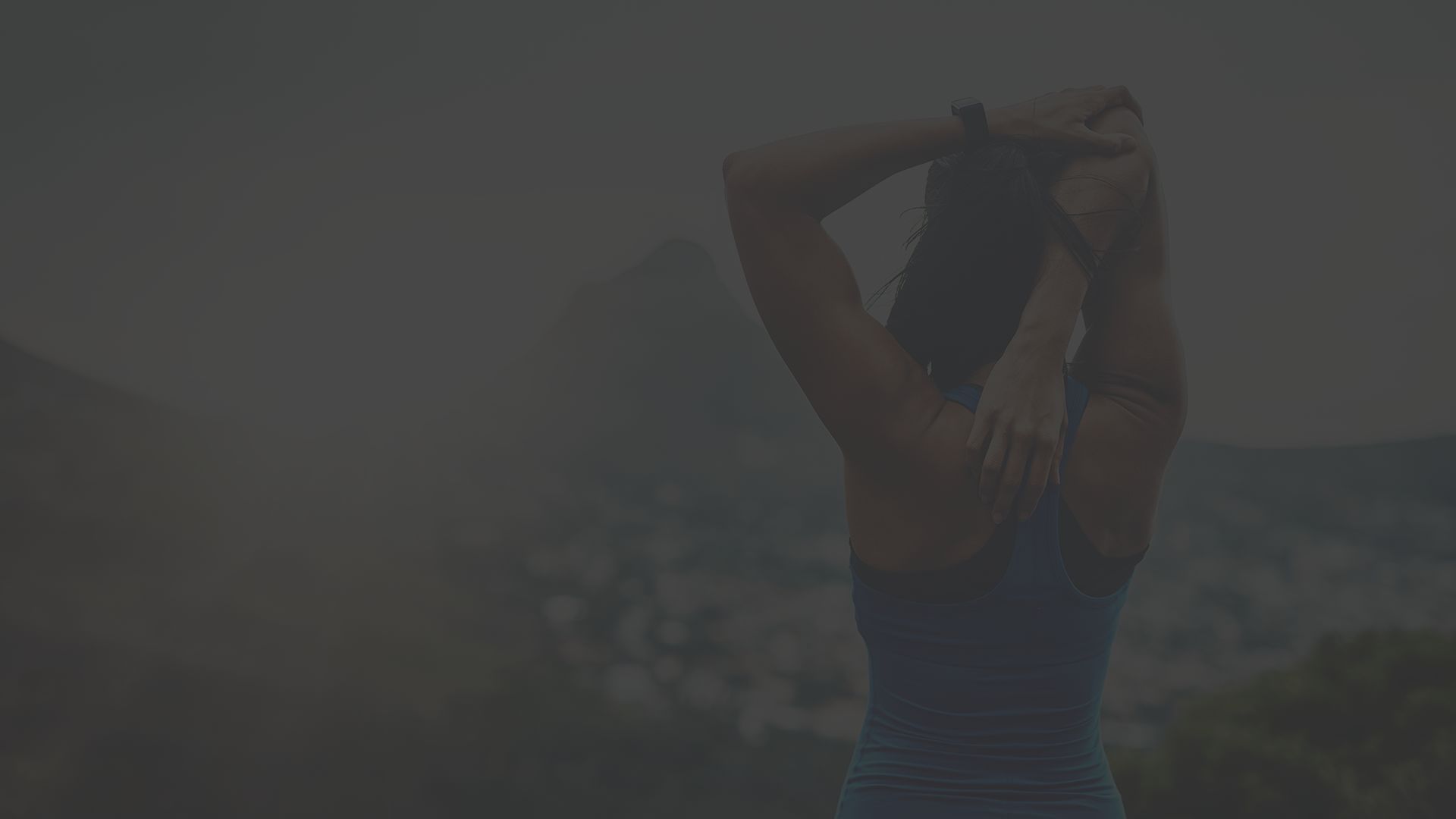 Strong woman stretching while staring off at mountains