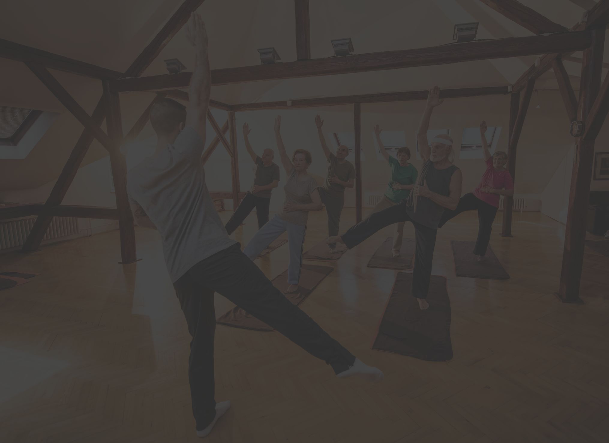 a group of older adults does a yoga class under the instruction of a yoga teacher