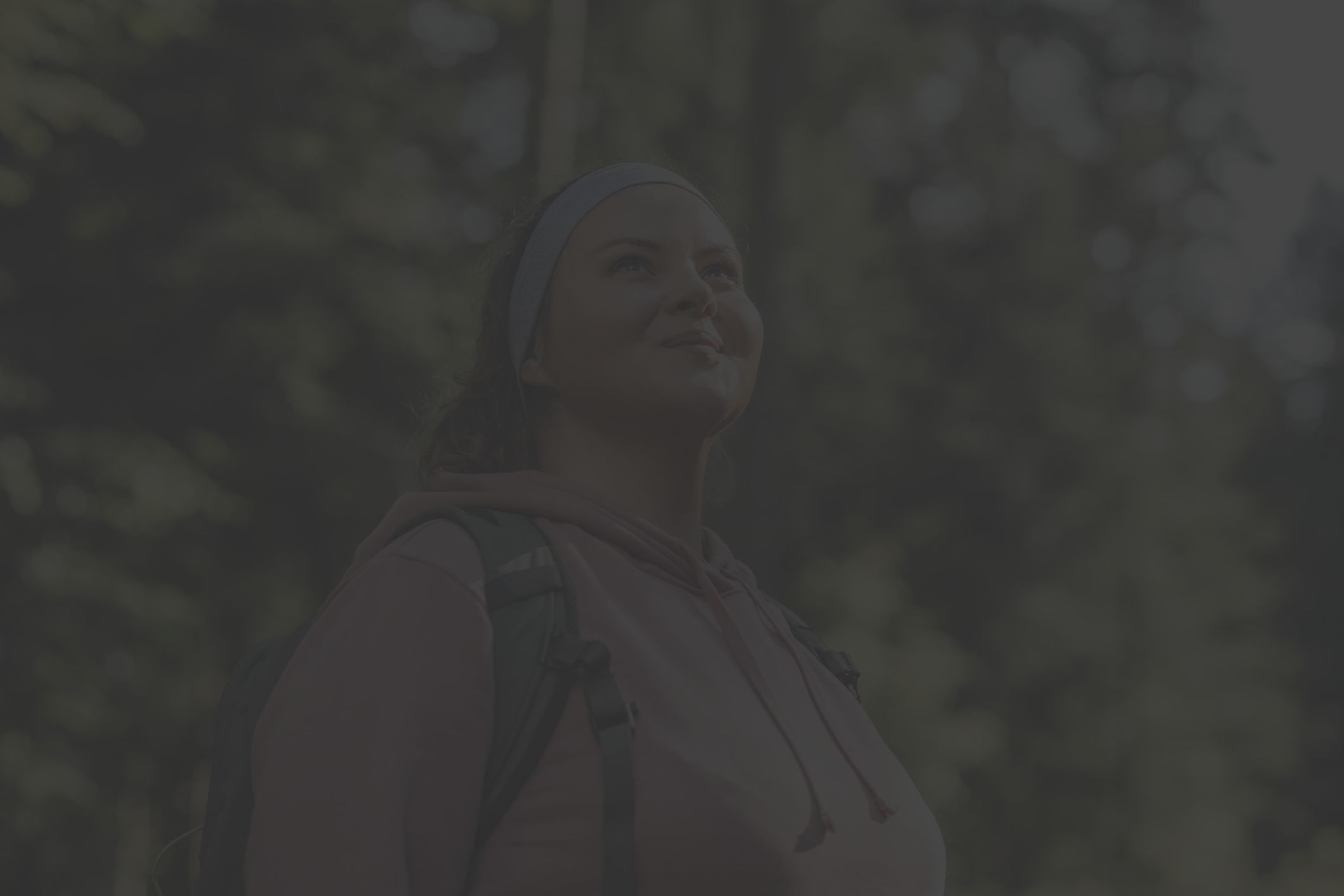 a fit overweight woman on a hike looks toward the sky