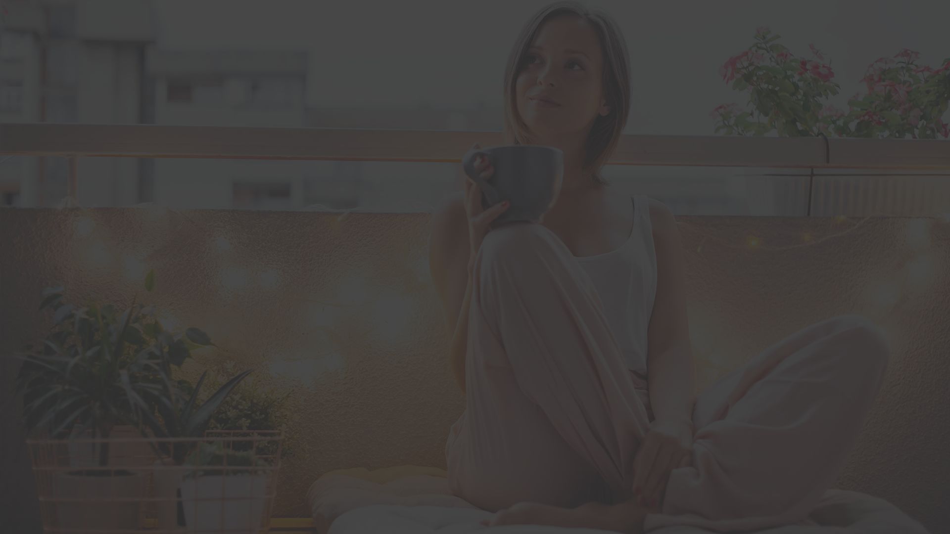 Happy woman surrounded by new home decor enjoying a cup of tea on a balcony.