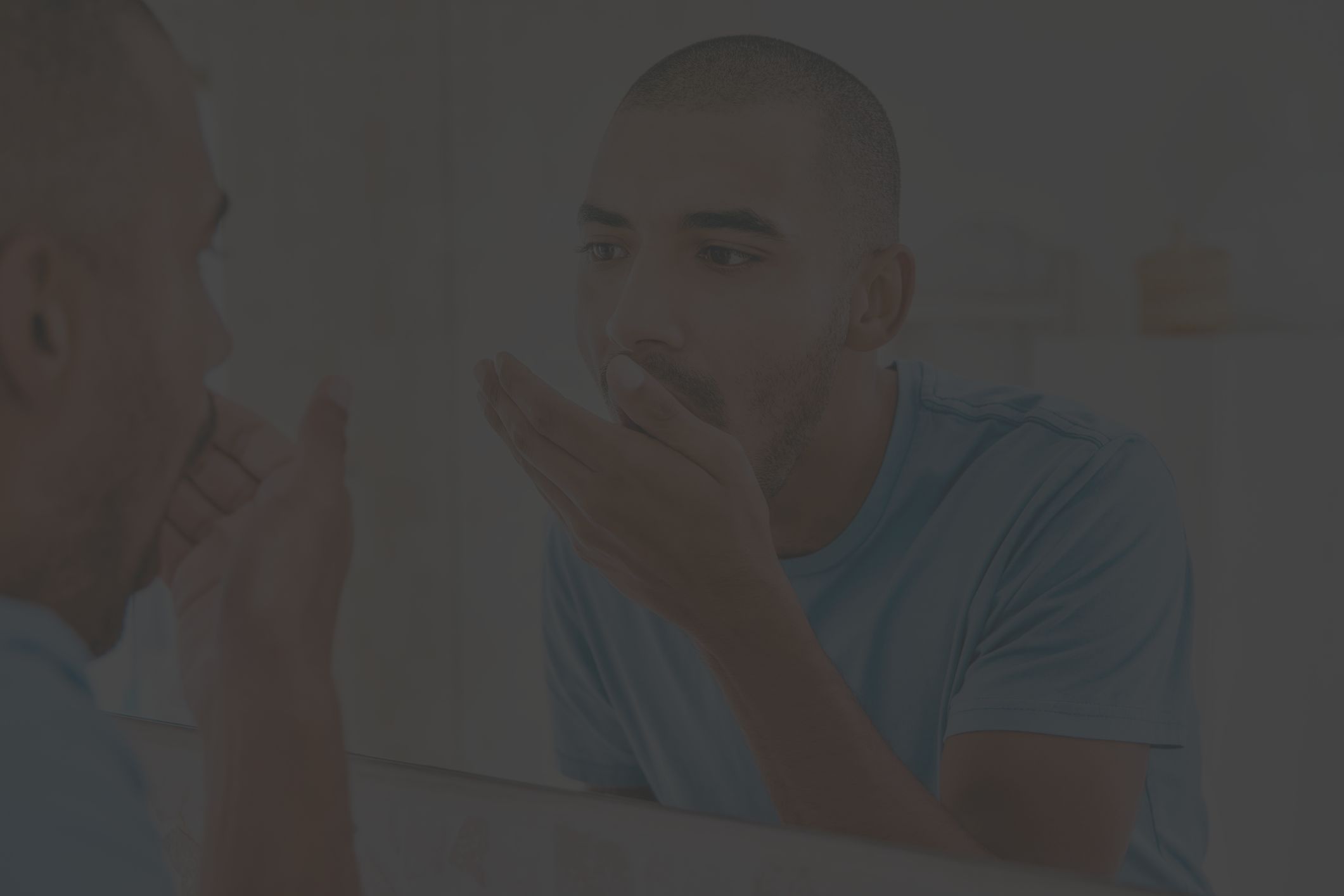 man checking his breath in the bathroom mirror