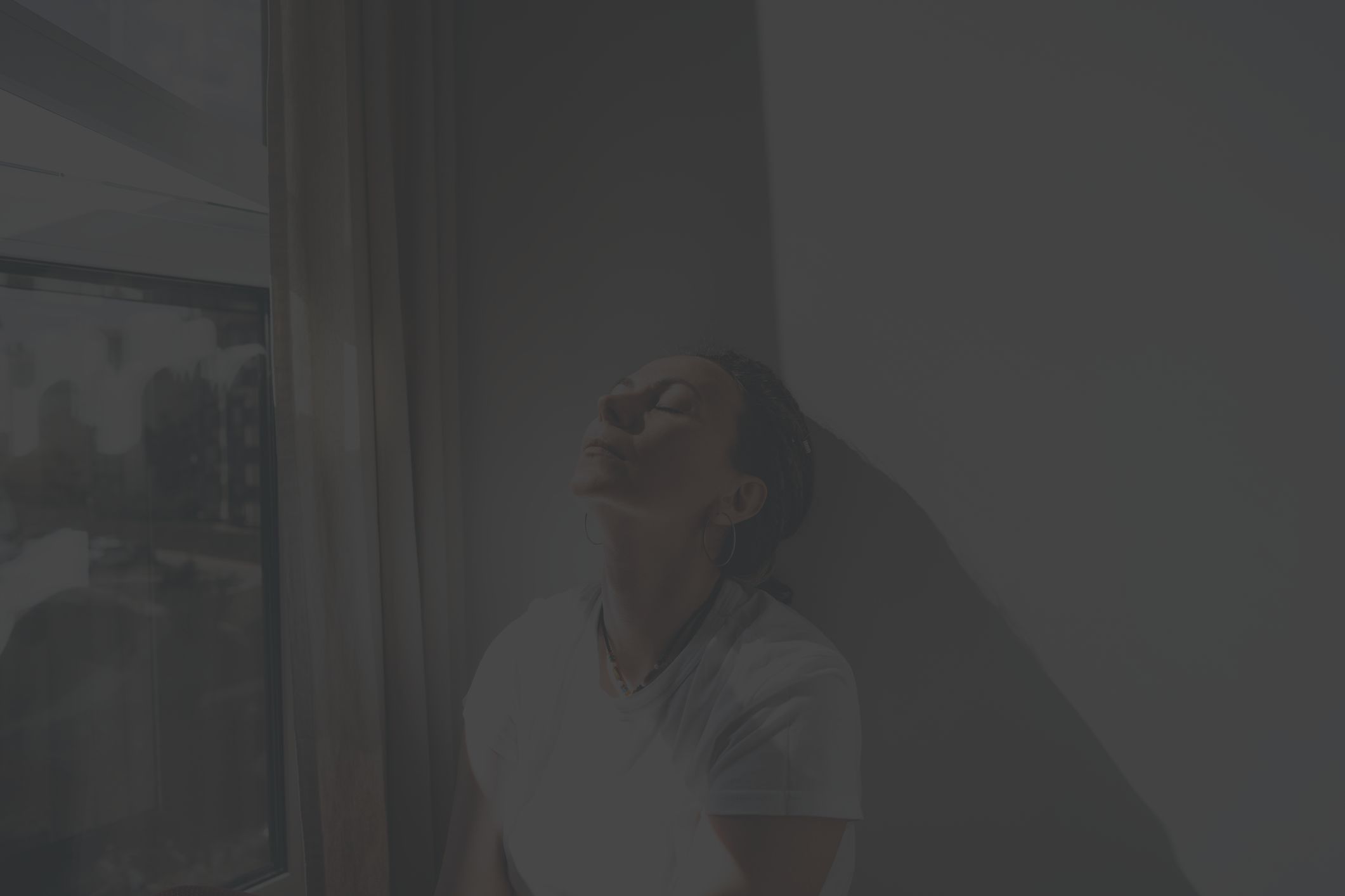 a middle aged white woman tries to soothe her anger by sitting against a wall and breathing