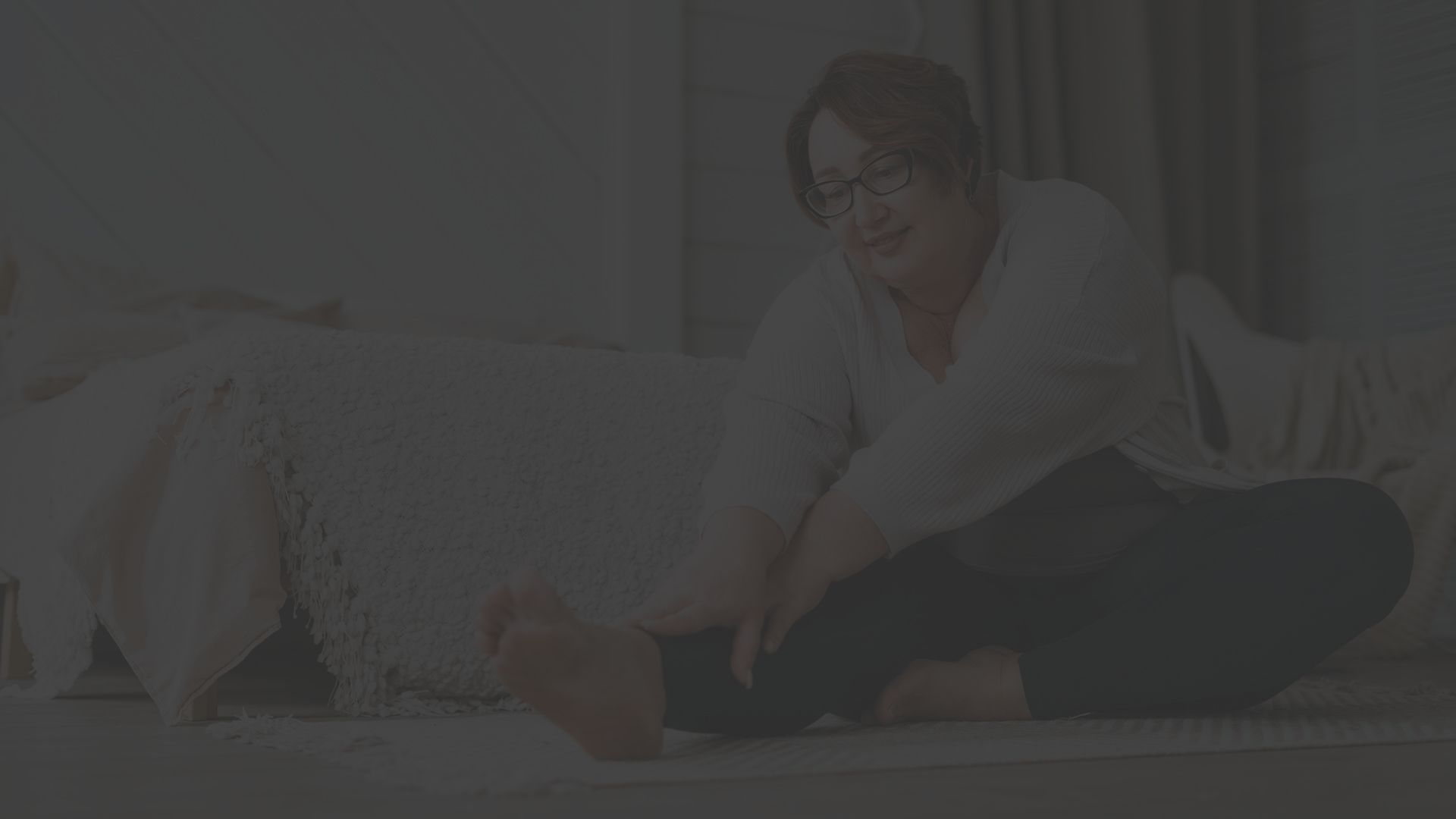 mature woman facing joint replacement surgery stretches in her bedroom
