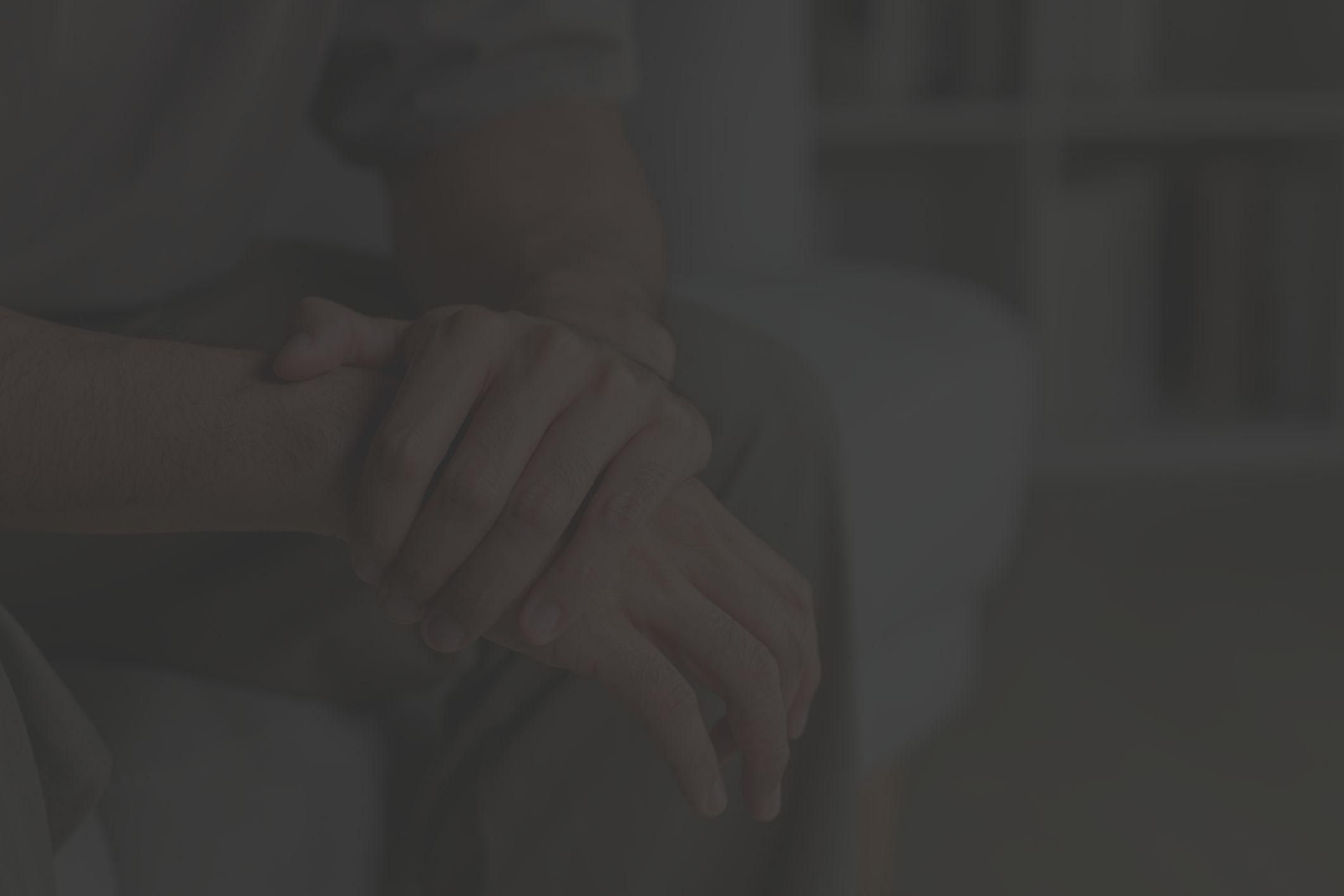 Close up of someone's being pensive and holding their hands while sitting on a couch