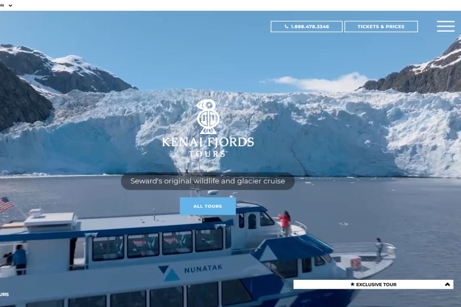 A tour boat named Nunatak navigates in front of a massive blue glacier and mountains.