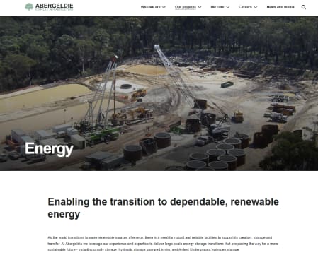 An aerial view of an energy construction site with large machinery, storage tanks, and excavated earth.